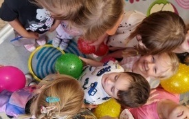 grupka dzieci stoi na dywanie niekt&oacute;re dzieci trzymają piłkę