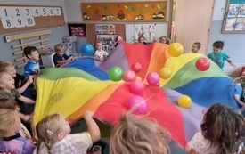 dzieci podrzucają piłki i balony na kolorowej chuście animacyjnej