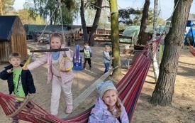 dzieci bawią się na r&oacute;żnych sprzętach na pierwszym olanie dziewczynka siedzi na hamaku