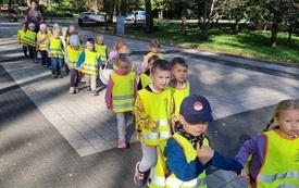 dzieci maszerują w parach po deptaku w parku miejskim