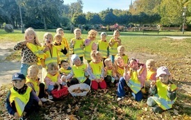 grupa dzieci w odblaskowych kamizelkach pozuje do zdjęcia grupowego w tle zgierski park