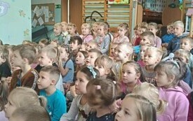 dzieci siedzą na dywanie i oglądają przedstawienie