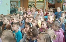 dzieci siedzą na dywanie i oglądają przedstawienie