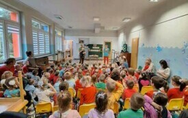 dzieci siedzą na dywanie i na krzesełkach oglądają jabłka i produkty z jabłek prezentowane przez nauczycielki w tle napis dzień jabłka