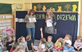 dzieci siedzą na dywanie dwie panie nauczycielki prezentują obrazki drzew