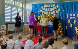 dwie panie odbierają nagrody od pani dyrektor i dw&oacute;ch dziewczynek po bokach panie nauczycielki widać dzieci obserwujące uroczystość