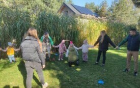 dzieci i dorośli w kole przekładają hula hop