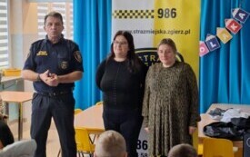 dwie nauczycielki i strażnik miejski stoją przed grupą dzieci w tle numer alarmowy do straży miejskiej