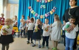 dzieci z upominkami pozują do zdjęcia w tle dekoracja "pasowanie na przedszkolaka"