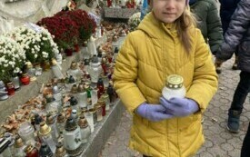 Dziewczynka stoi ze zniczem w ręku