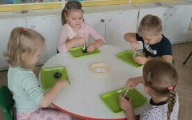 Dzieci wykonują zadanie przy stole. 