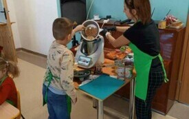 Chłopiec i prowadząca robią w maszynie pastę na tortille. 
