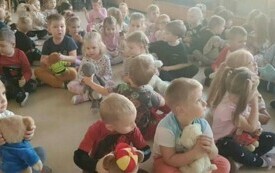 Dzieci siedzą na dywanie. 