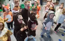 dzieci w przebraniach aniołk&oacute;w oraz r&oacute;znych zwierząt stoją w grupie w tle świąteczna dekoracja