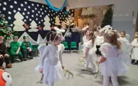 dziewczynki w przebraniach aniołk&oacute;w trzymają w dłoniach złote dekoracje