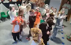 dzieci w przebraniach aniołk&oacute;w oraz r&oacute;znych zwierząt stoją w grupie w tle świąteczna dekoracja