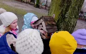 grupa dzieci przed karmnikiem w ogrodzie