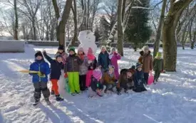 grupa dzieci pozuje na śniegu w tle zimowy krajobraz i bałwan