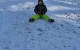 dziecko zjeżdża z g&oacute;rki w tle nauczycielka i inne dzieci