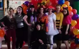 panie nauczycielki w kolorowych przebraniach pozują do zdjęcia na tle łuku z balonami nad nimi serpentyny