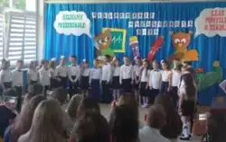 dzieci w odświętnych strojach stoją obok siebie, w tle dekoracja żegnamy przedszkole, czas pomyśleć o szkole