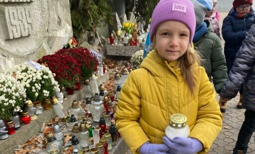 Dziewczynka stoi ze zniczem w ręku