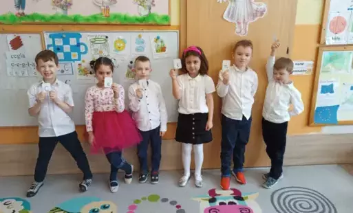 dzieci stoją w szeregu każdy trzyma literę