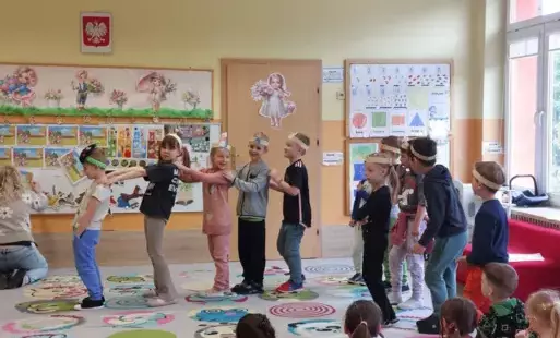dzieci w opaskach na głowach stoją w rzędzie trzymając się za ramiona
