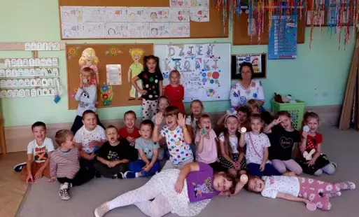 dzieci wraz z nauczycielką pozują do zdjęcia, w tle widać dekorację na dzień kropki