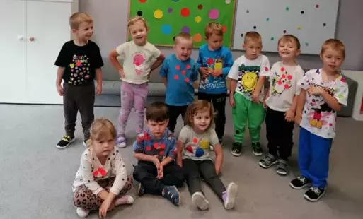 grupka dzieci pozuje do zdjęcia w tle zielona dekoracja dzień kropki