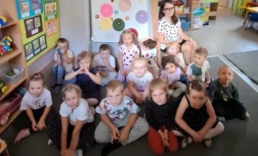 grupa dzieci wraz z panią nauczycielką pozują do zdjęcia w tle dekoracja dzień kropki