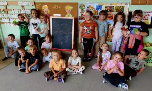 dzieci pozują do zdjęcia grupowego na środku stoi tablica z napisem dzień przedszkolaka 2025 w grupie 6