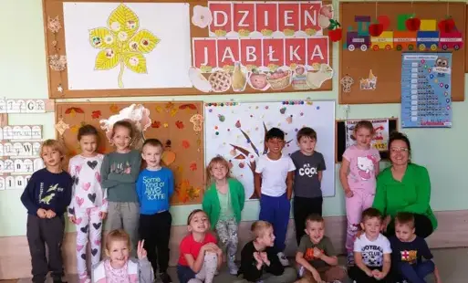 grupa dzieci pozuje do zdjęcia wraz z panią w tle dekoracje dzień jabłka