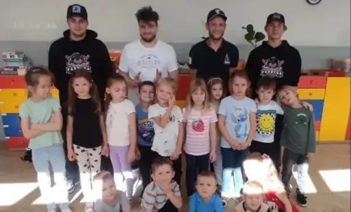 grupa dzieci pozuje do zdjęcia grupowego za nimi stoją czterej panowie
