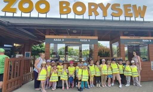 grupa dzieci wraz z nauczycielkami pozują do zdjęcia grupowego na tle wejścia do Zoo Borysew