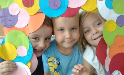 troje dzieci pozuje do zdjęcia w fotoramce z kolorowych kółek
