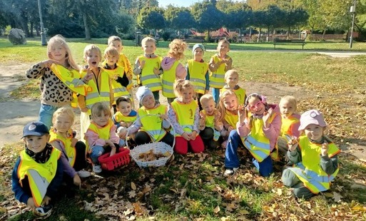 grupa dzieci w odblaskowych kamizelkach pozuje do zdjęcia grupowego w tle zgierski park